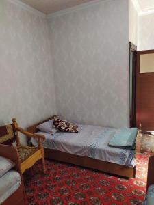 1 dormitorio pequeño con 1 cama y 1 silla en Masturabonu Ravshan, en Bukhara