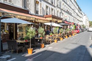 a street with tables and chairs and umbrellas at Happy Stay Paris - Cosy Studios - 5 min to Eiffel Tower in Paris