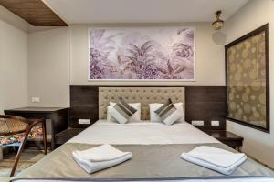 莫爾吉姆的住宿－Skon Morjim Beach Resort by Orion Hotels，卧室配有一张大床,墙上挂有绘画作品