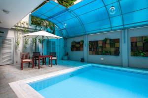 a pool with a table and chairs and an umbrella at Royal Park Residence Hotel in Dhaka