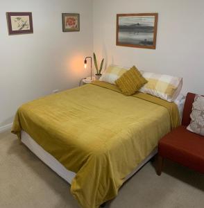 1 dormitorio con 1 cama con colcha amarilla y silla en Private Room with Ensuite en Yass