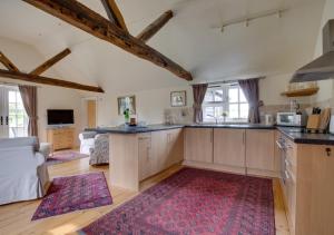 une cuisine avec des placards en bois et un tapis rouge dans l'établissement Pound Hill Cottage, à Frittenden