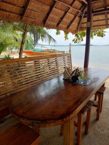 a wooden table in front of a beach with the ocean at Concepcion Divers Lodge in Busuanga