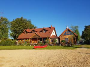 a house with a red boat in front of it at Dolina Biebrzy - Chata Flisaka in Wroceń