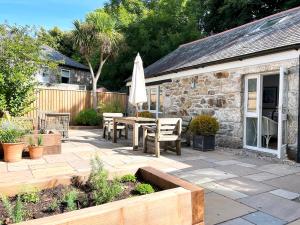 a patio with a table and an umbrella at Idyllic Country Cottage near Marazion & St Ives in Penzance