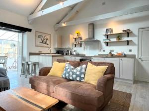 a living room with a brown couch and a kitchen at Idyllic Country Cottage near Marazion & St Ives in Penzance