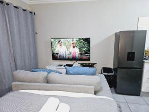 a living room with two couches and a flat screen tv at Quantum Heights - Studio Apartment in Fourways
