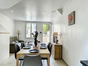 a dining room with a table and chairs in a living room at La Deauvilloise YourHostHelper in Deauville