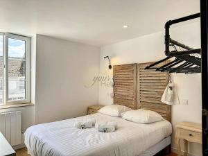 um quarto com uma grande cama branca e 2 almofadas em La Deauvilloise YourHostHelper em Deauville