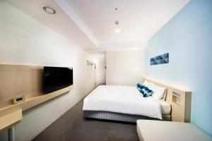 a hotel room with a bed and a flat screen tv at Hotel Torifito Miyakojima Resort in Miyako-jima