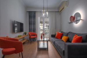 un soggiorno con divano grigio e cuscini arancioni di Estia Thessaloniki Apartment, cozy, spacious, sunny, 2 rooms-5 beds a Salonicco