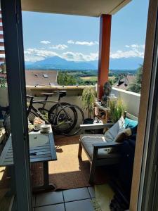 einen Balkon mit Sofa, Tisch und Fahrrad in der Unterkunft Charmant appartement avec magnifique vue in Monnetier-Mornex