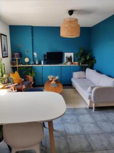 sala de estar con sofá blanco y pared azul en Charmant appartement avec magnifique vue, en Monnetier-Mornex