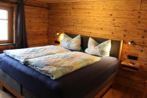 Panoramahof Monika Kennerknecht في Akams: غرفة نوم بسرير في جدار خشبي