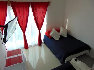 1 dormitorio con 1 cama y una ventana con cortinas rojas en Departamentos Villas Capdeviel, en Cancún
