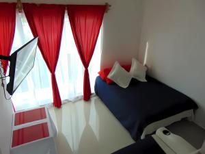 una camera da letto con un letto e una finestra con tende rosse di Departamentos Villas Capdeviel a Cancún