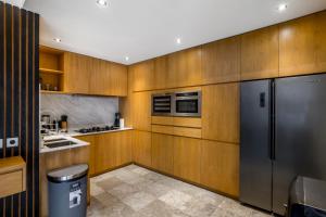 eine Küche mit Holzschränken und einem Edelstahlkühlschrank in der Unterkunft Villa Iris by BaliSuperHost in Dalung