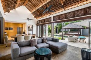 ein offenes Wohnzimmer mit einem Sofa und einem Tisch in der Unterkunft Villa Iris by BaliSuperHost in Dalung