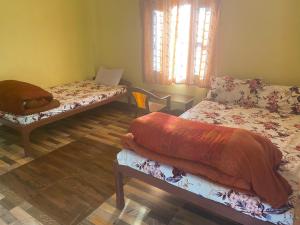 a room with two beds and a window at KB'S ECO MOUNTAIN VILLAGE HOME in Kāskī