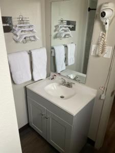 a bathroom with a sink and a mirror at Artesia Inn- No Service Fees in Artesia