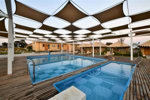 a swimming pool with a roof over it at The Fern Seaside Luxurious Tent Resort Diu in Diu