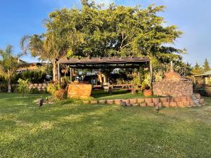 a pavilion in a yard with a stone wall at Moonriver Cottage, Prime Lagoon Views & Solar Power in Knysna