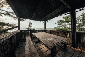 een houten tafel op een veranda met uitzicht op de oceaan bij Beach Home for Nature Lovers in Bernāti