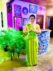 a woman in a yellow and green dress standing in a room at Manel Guest House in Polonnaruwa