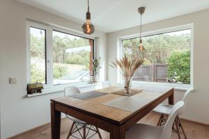a dining room with a wooden table and white chairs at Beach Home for Nature Lovers in Bernāti