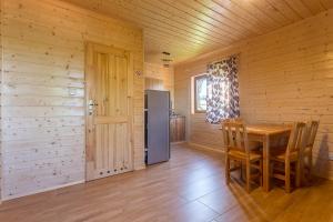 una sala da pranzo con tavolo e frigorifero di PANORAMA Domki i Pokoje Nad Jeziorem 660-332-576 a Polańczyk