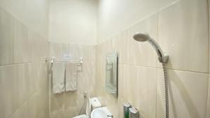 a white bathroom with a shower and a toilet at Cemara Asri INN in Pulauberayan Dadap