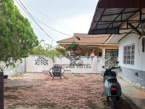 a scooter parked in front of a house at Ventura Hotel and Tours in Gua Musang