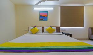 Un dormitorio con una cama grande con almohadas amarillas y coloridas en Itsy By Treebo - N Square, en Vijayawāda