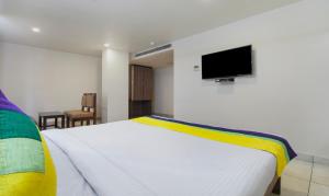 Schlafzimmer mit einem weißen Bett und einem Flachbild-TV in der Unterkunft Itsy By Treebo - N Square in Vijayawāda