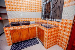 an orange kitchen with a sink and a mirror at Niwa Apartments in Dar es Salaam