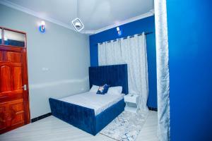 1 dormitorio con paredes azules, 1 cama y puerta en Niwa Apartments, en Dar es Salaam