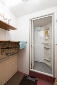 W łazience znajduje się prysznic ze szklanymi drzwiami. w obiekcie Backstage Party Hostel & Bar w Osace