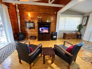 a living room with two chairs and a television at Moonriver Cottage, Prime Lagoon Views & Solar Power in Knysna