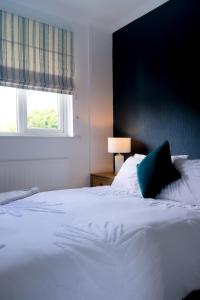 Cama blanca con almohada azul y ventana en Amroth House, en Cardiff