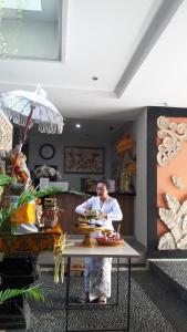 a man standing next to a table with food on it at The Agung Residence in Seminyak