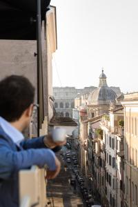 un hombre sosteniendo una taza de café en un balcón en Condominio Monti Boutique Hotel en Roma