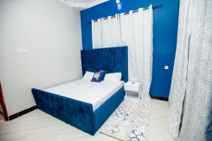 Schlafzimmer mit einem Bett mit blauem Kopfteil in der Unterkunft Niwa Apartments in Daressalam