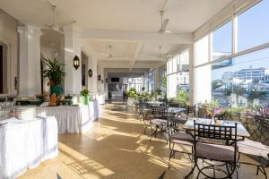 - une salle à manger avec des tables, des chaises et des fenêtres dans l'établissement Sentrim Castle Royal Hotel, à Mombasa