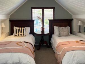 1 dormitorio con 2 camas y 1 mesa con ventana en Dunvegan Lodge en Clovelly
