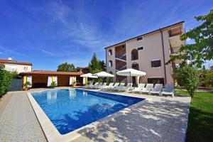 a swimming pool with white chairs and a building at Villa Tina in Novigrad Istria