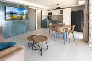 בית חוף מושלם עם גקוזי ומרפסת - Beachside Bliss W jacuzzi في حيفا: مطبخ وغرفة معيشة مع طاولة وكراسي