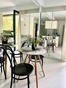 a dining room with a table and chairs and a kitchen at Mirror Apartment in Serock