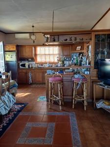 a kitchen with wooden cabinets and bar stools at To spiti tis Xaras in Agia Anna