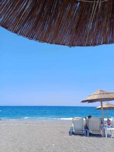 two chairs and an umbrella on a beach at To spiti tis Xaras in Agia Anna