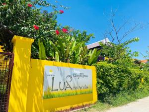 un letrero amarillo en una valla con flores en Chez Mimosa Hoi An - LUA Retreat, en Hoi An